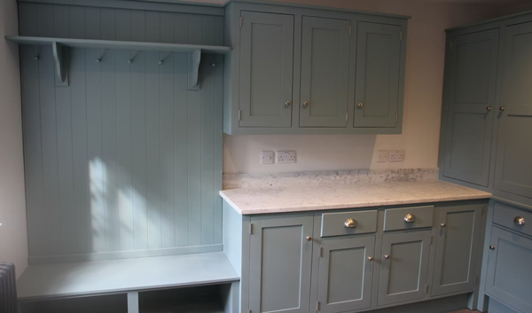 kitchen interior with light blue cabinets and countertop including a section with hooks and a bench for two